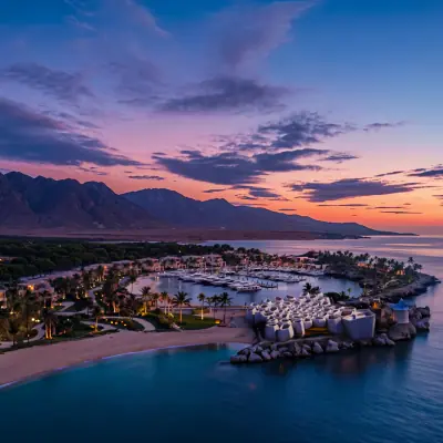 Aerial sunset view of luxury marina resort surrounded by mountains and coastline