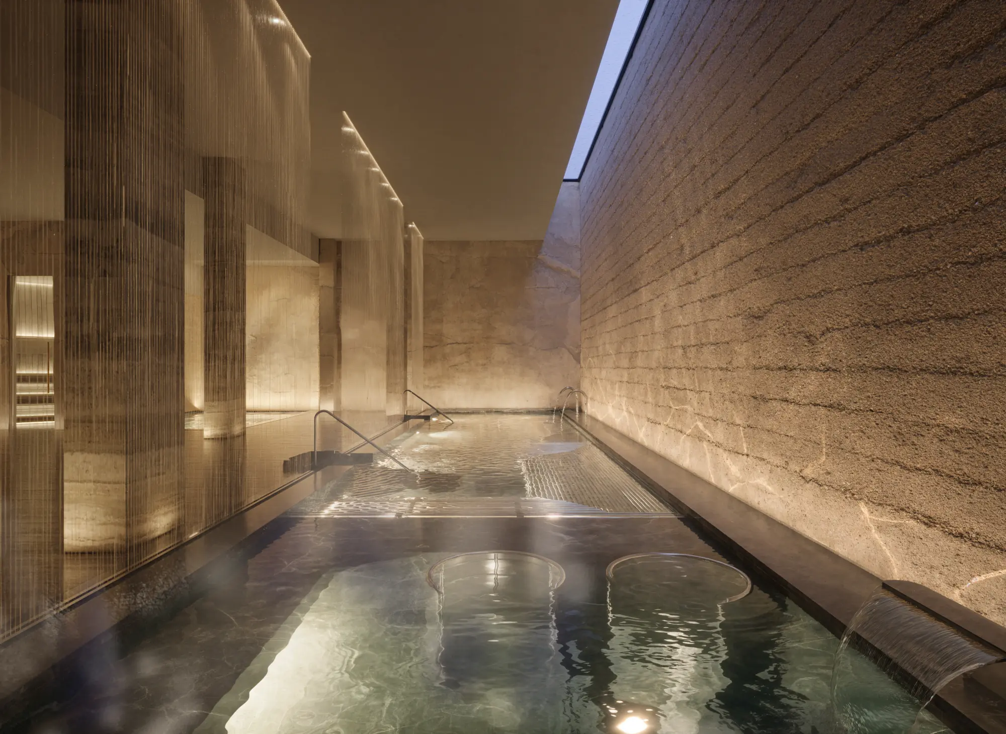 Daytime hydrotherapy spa grotto with heated pools and textured stone walls