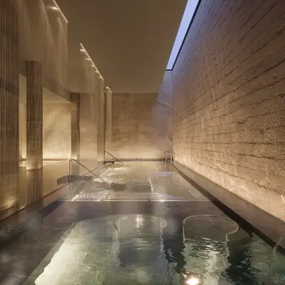 Daytime hydrotherapy spa grotto with heated pools and textured stone walls