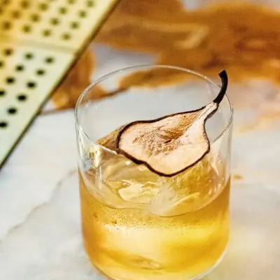 Signature wellness cocktail with dried pear garnish