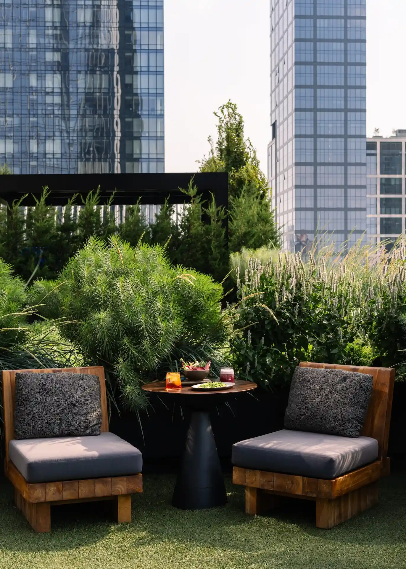 Two cushioned chairs and table with salad, green beans and drinks in lush urban garden setting