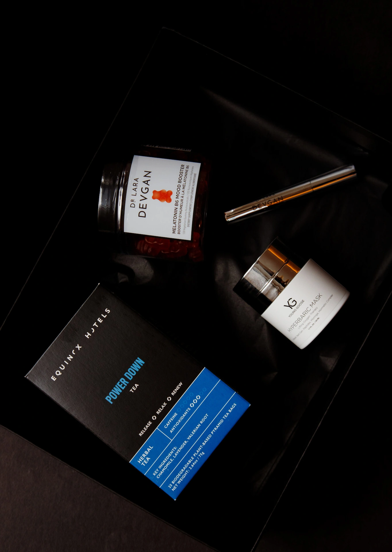 Luxury wellness kit with supplements, skincare, and herbal tea arranged in black box for relaxation