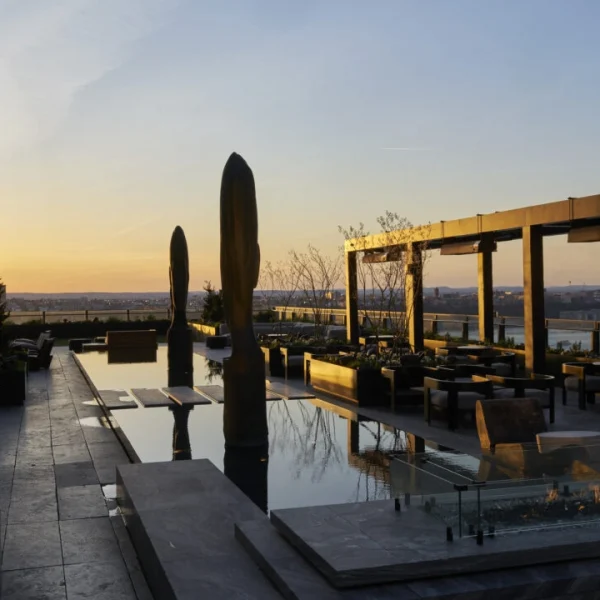 Equinox rooftop terrace at sunset with water feature, sculptural elements, fire pit, pergola and city view