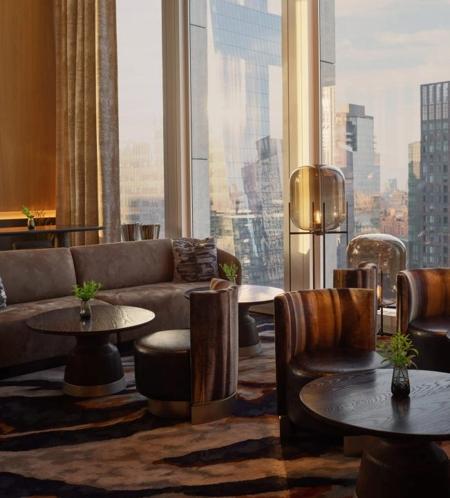 Modern lounge with curved sofa, woodgrain armchairs, city view and foliage on round tables