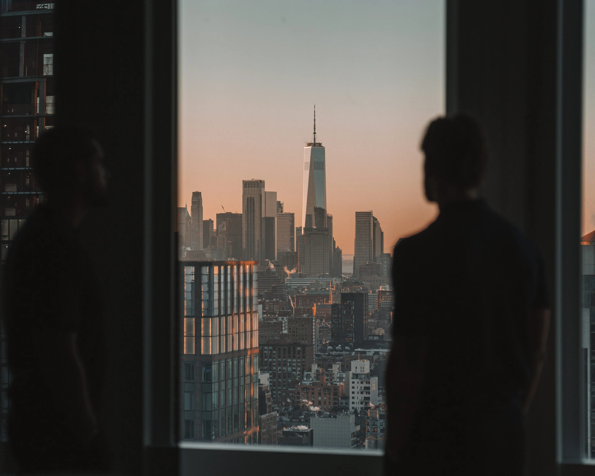 Sunset view of Lower Manhattan from Equinox Hotel, with One World Trade Center framed by large window.