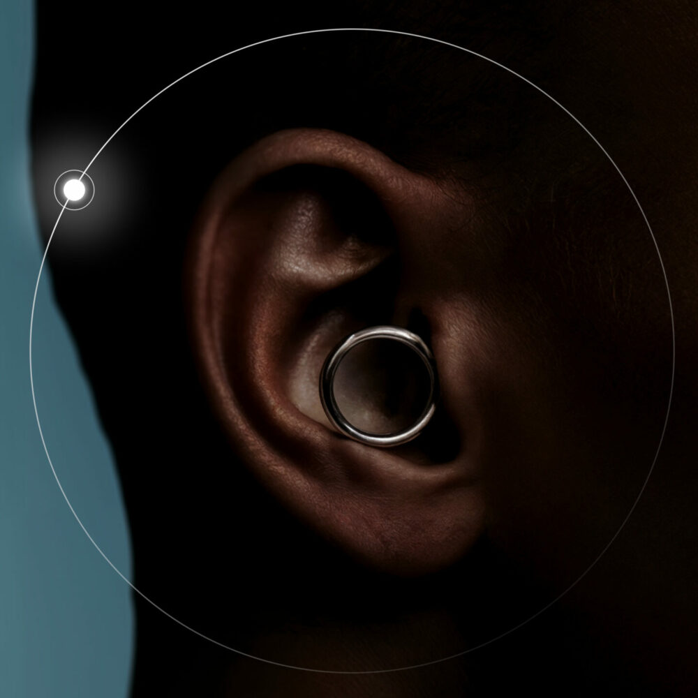 Close‑up of an ear with a large circular gauge earring, set against a blue background with overlaid circular graphics.