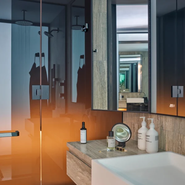 Minimalist bathroom with gradient glass shower, stone vanity, and curated amenities, evoking modern clarity and intimate refinement