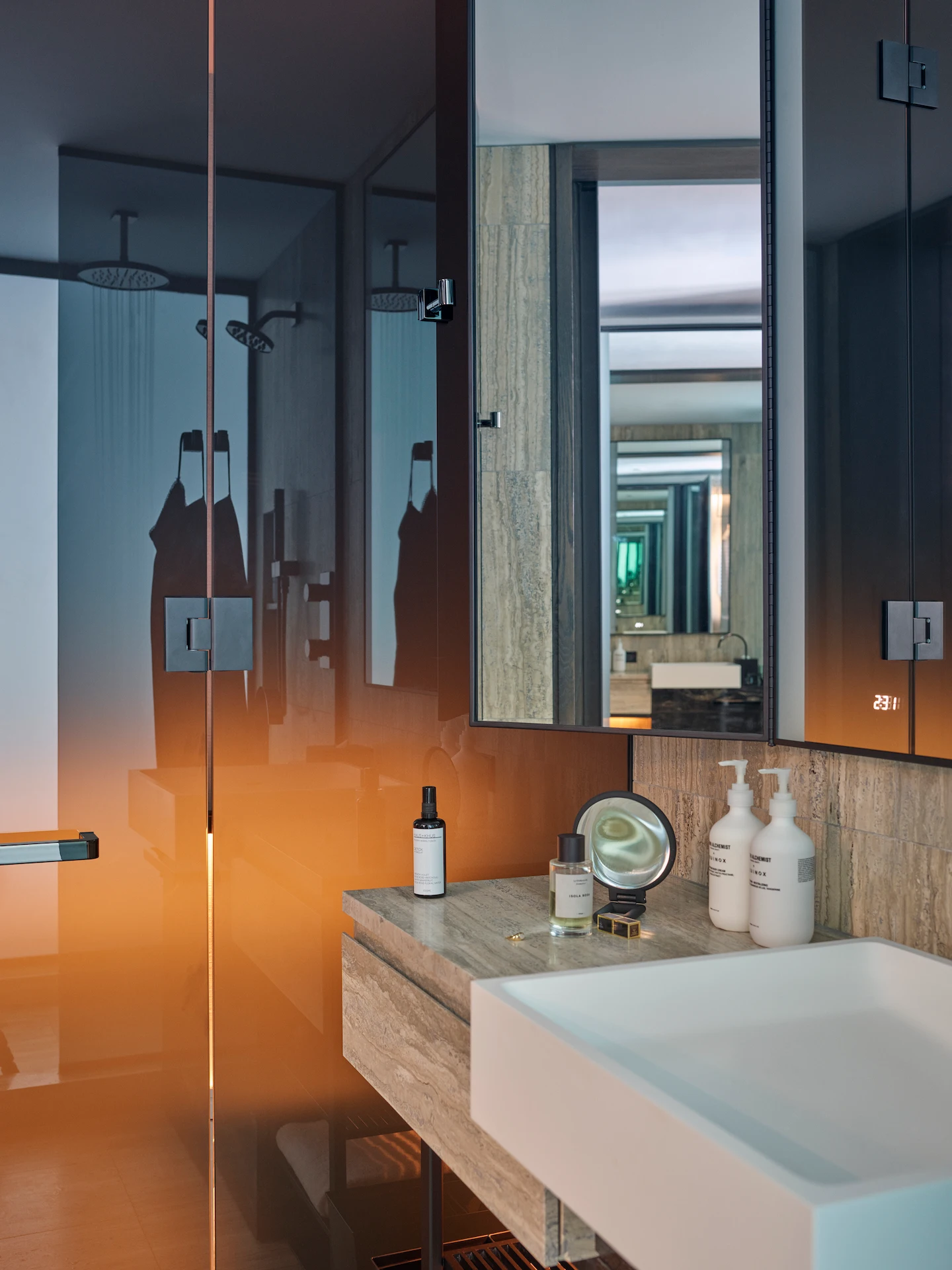 Minimalist bathroom with gradient glass shower, stone vanity, and curated amenities, evoking modern clarity and intimate refinement