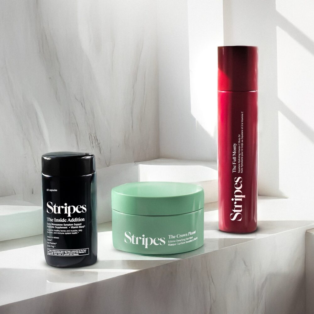 Three Stripes skincare products on marble: probiotic supplement, cream mask, and firming serum.