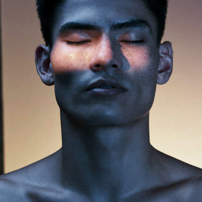 Close‑up of person with eyes closed at Equinox Hotel, dramatic lighting with blue tones and warm strip across face.