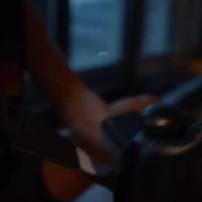 Person preparing for boxing training, putting on gloves with focused expression in a softly lit indoor gym setting.