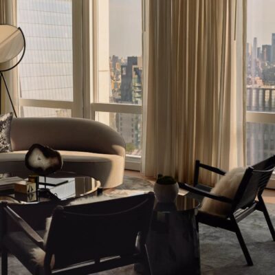 Elegant living room with curved beige sofa, black coffee table, and panoramic city view featuring One World Trade Center.