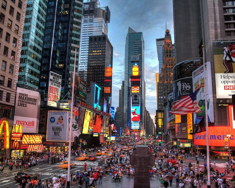 Times Square at night with crowds, taxis, and bright billboards including McDonald's and Coca-Cola.
