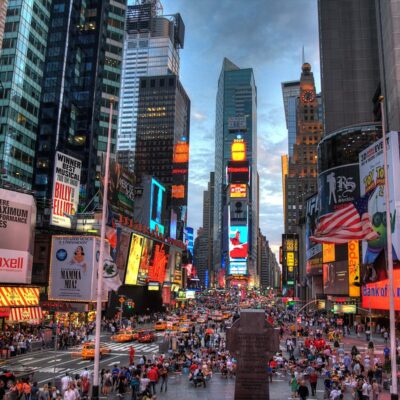 Times Square at night with crowds, taxis, and bright billboards including McDonald's and Coca-Cola.