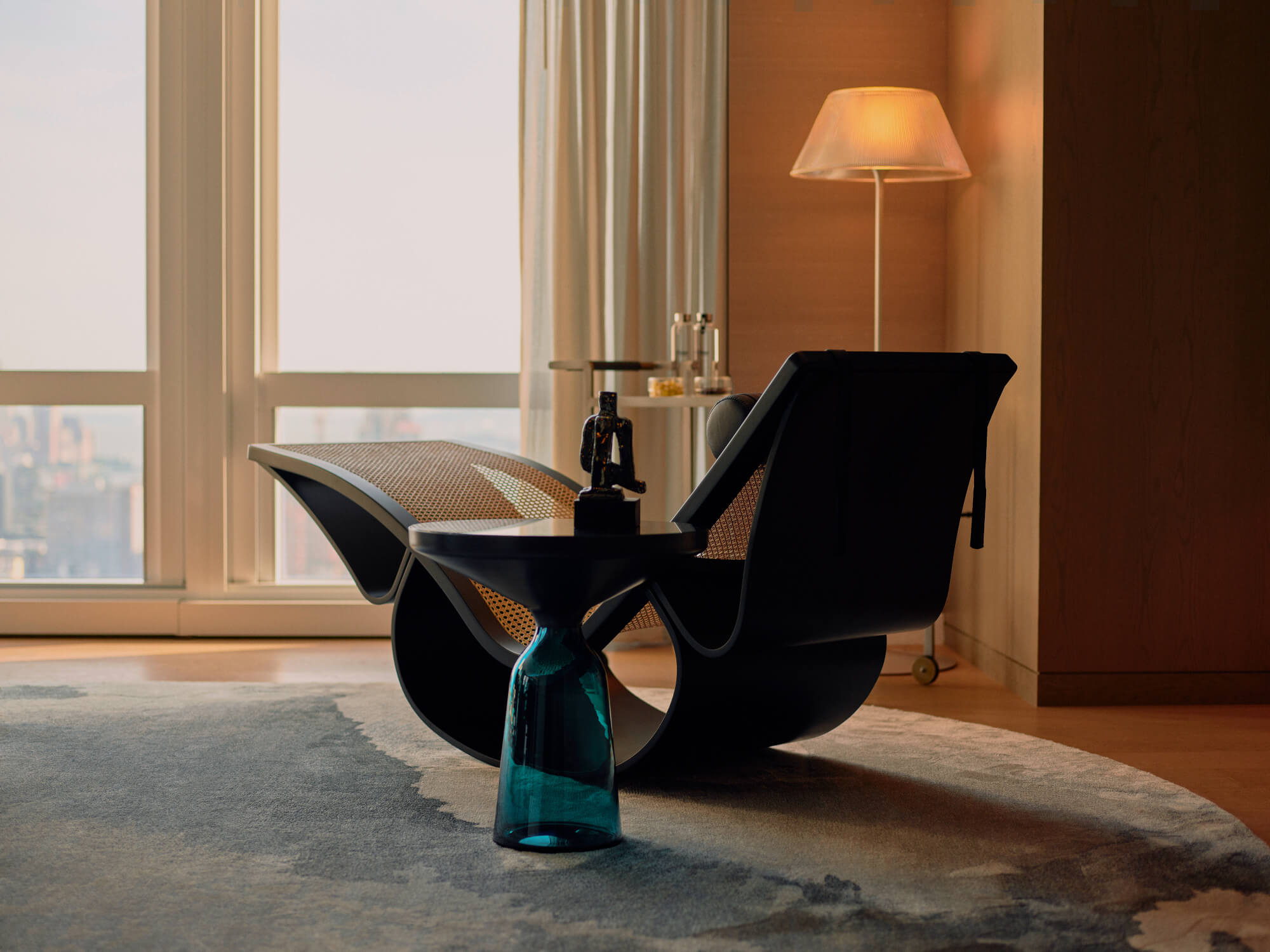 Stylish lounge chair with curved frame, rattan panels, and city view through sheer curtains.