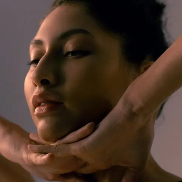 Woman performing facial massage on herself in a serene setting with soft lighting and a calm atmosphere