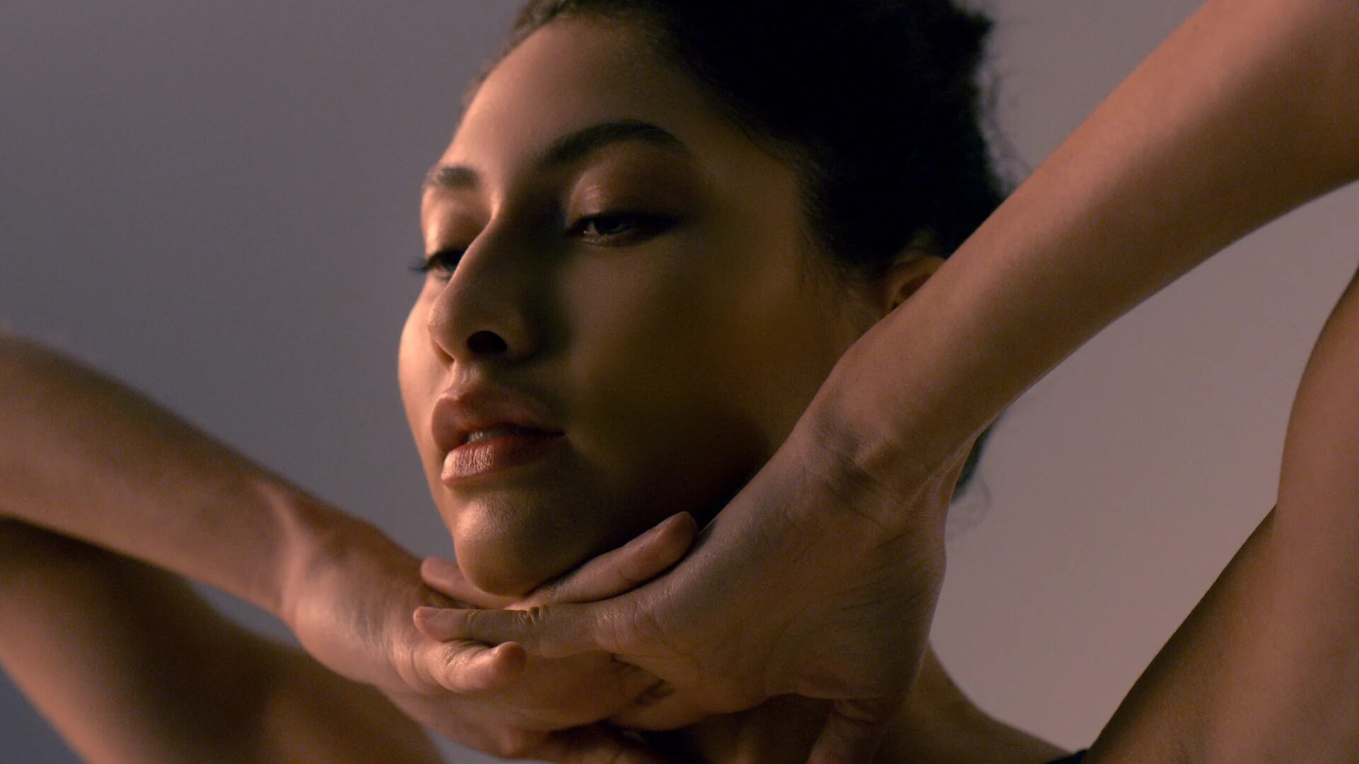 Woman performing facial massage on herself in a serene setting with soft lighting and a calm atmosphere
