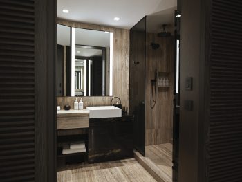 Modern bathroom with wood-textured tiles, black vanity, and glass shower under recessed lighting.