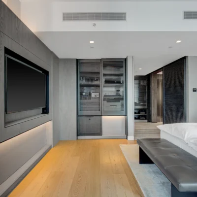Contemporary bedroom with white linens, wood accents, and built-in workspace, evoking quiet luxury and functional elegance