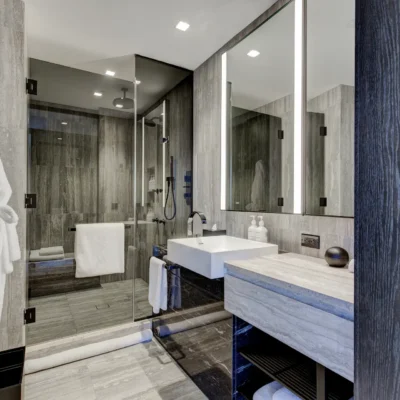 Elegant bathroom with glass shower, dual robes, and stone vanity, evoking spa-like calm and modern refinement