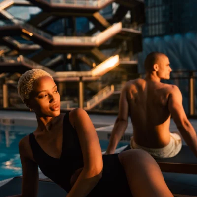 Couple relaxing by the rooftop pool at Equinox Hotel New York with sunset views of the Vessel at Hudson Yards.
