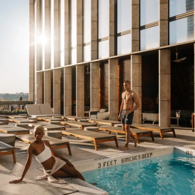 Guests enjoying the outdoor poolside at Equinox Hotel New York, with modern lounge chairs and city views at sunset.