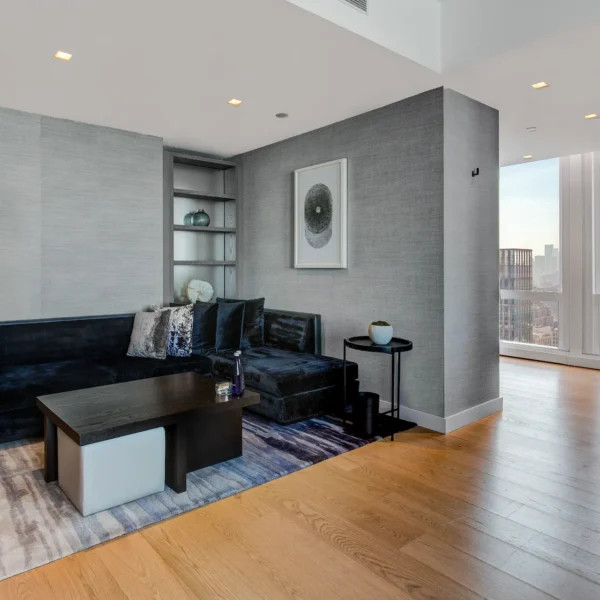 Modern living room with dark sectional sofa, abstract art, and city views, evoking quiet sophistication and urban comfort