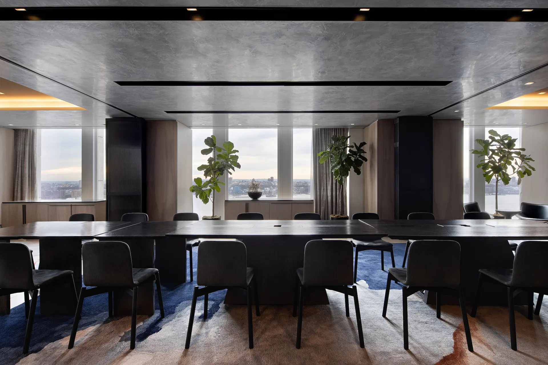 Modern conference room at Equinox Hotel New York with a large polished table, floor-to-ceiling windows showcasing sweeping city views, abundant natural light, and curated greenery, creating an inspiring and professional meeting environment.