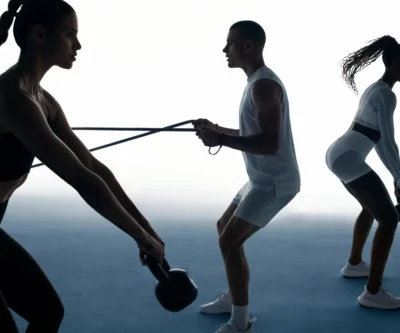 Three people training with kettlebells and resistance bands against minimal gradient background, highlighting motion and silhouette