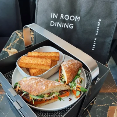 Tray with sandwich halves and toasted bread sticks, on marble table with Equinox Hotels bag.