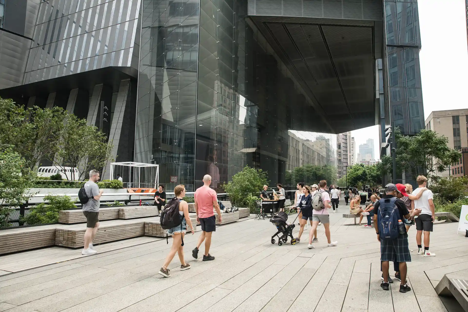 Modern city plaza with people walking and relaxing among trees, benches, and sleek architecture, evoking urban connection and open-air vitality