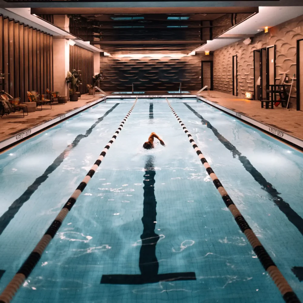 Guest swimming underwater in luxury pool at Equinox NYC, showcasing serene ambiance & modern design details.