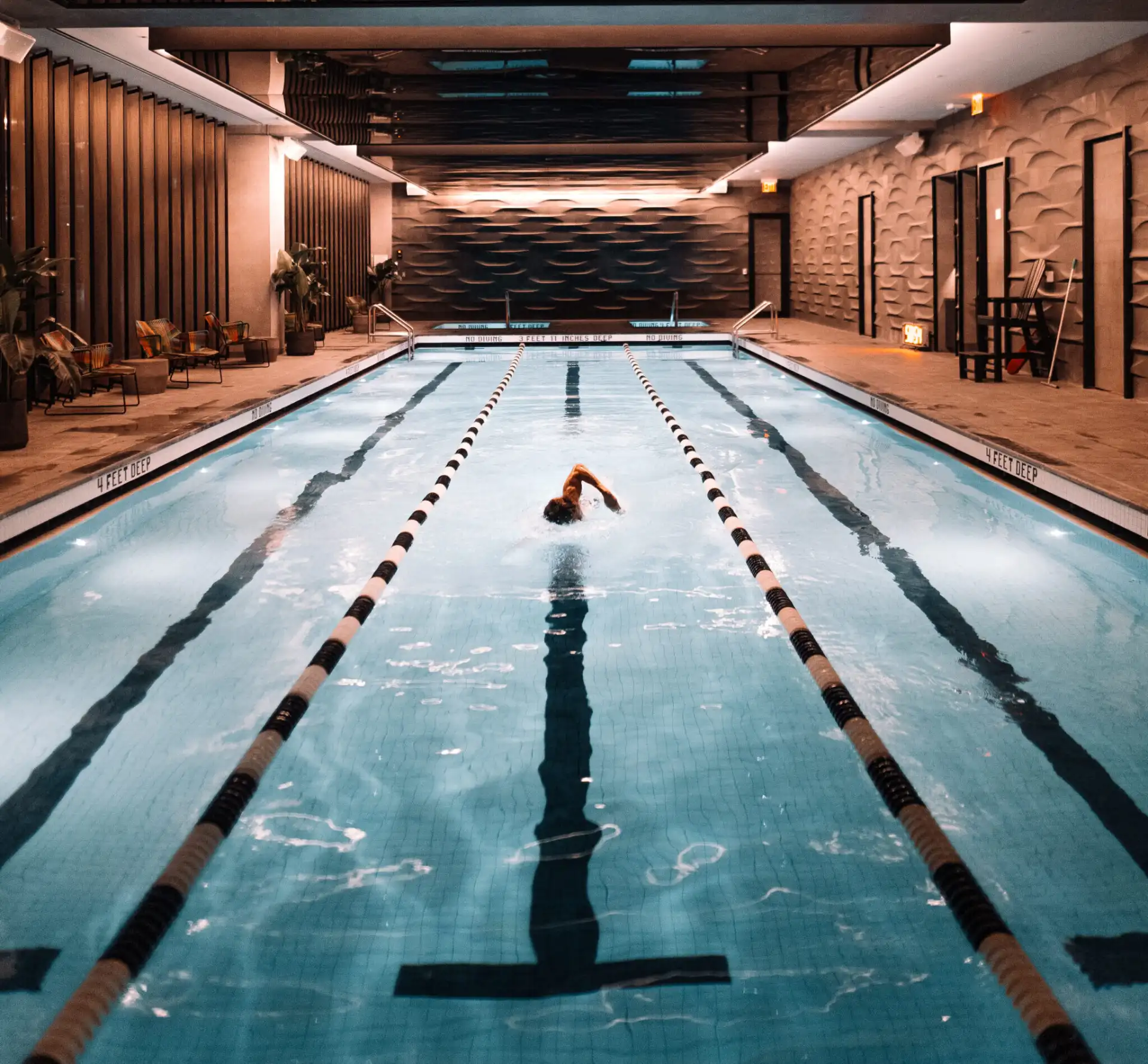 Guest swimming underwater in luxury pool at Equinox NYC, showcasing serene ambiance & modern design details.