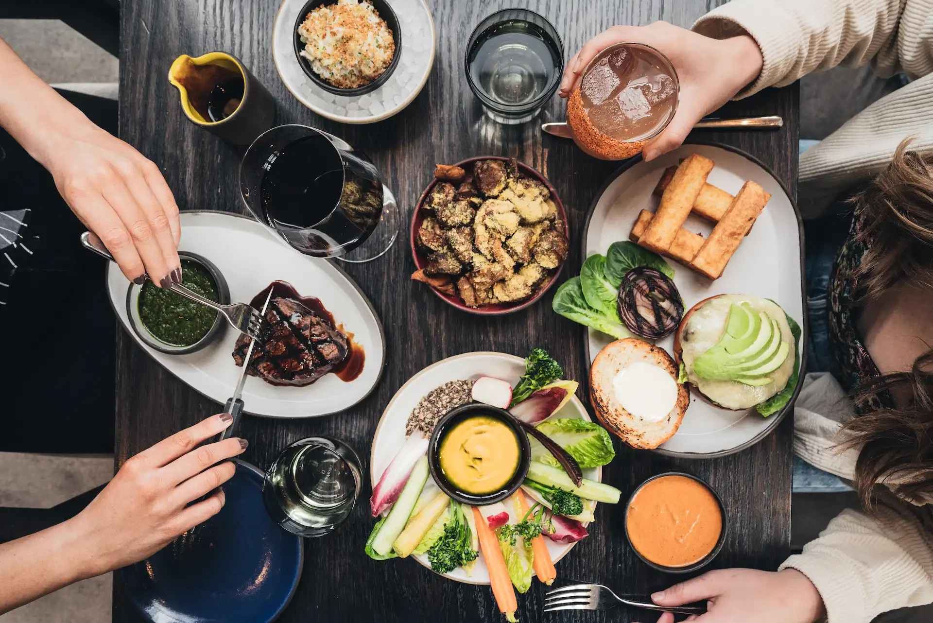 Top-down view of a shared dining table adorned with colorful, artfully plated dishes and drinks, with two people enjoying a vibrant meal that evokes connection, warmth, and a lively culinary experience.