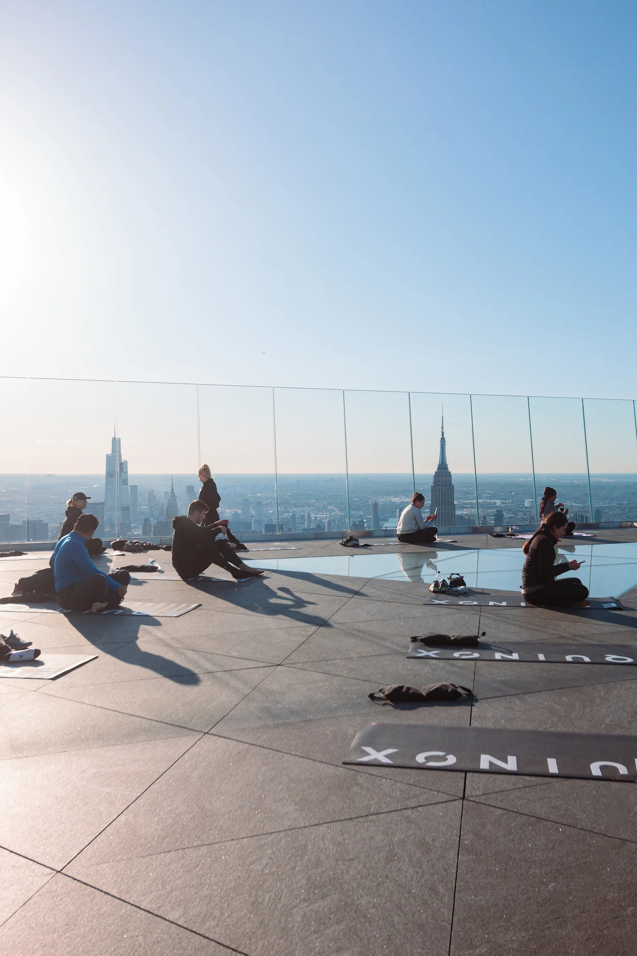 Group rooftop yoga session with Equinox mats and panoramic skyline, blending movement, mindfulness, and metropolitan energy