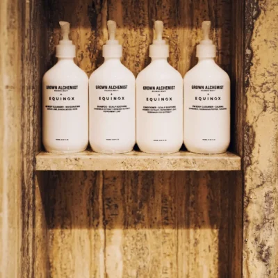 Set of Grown Alchemist x Equinox body care products arranged on stone shelf, evoking luxury wellness and curated in-room rituals