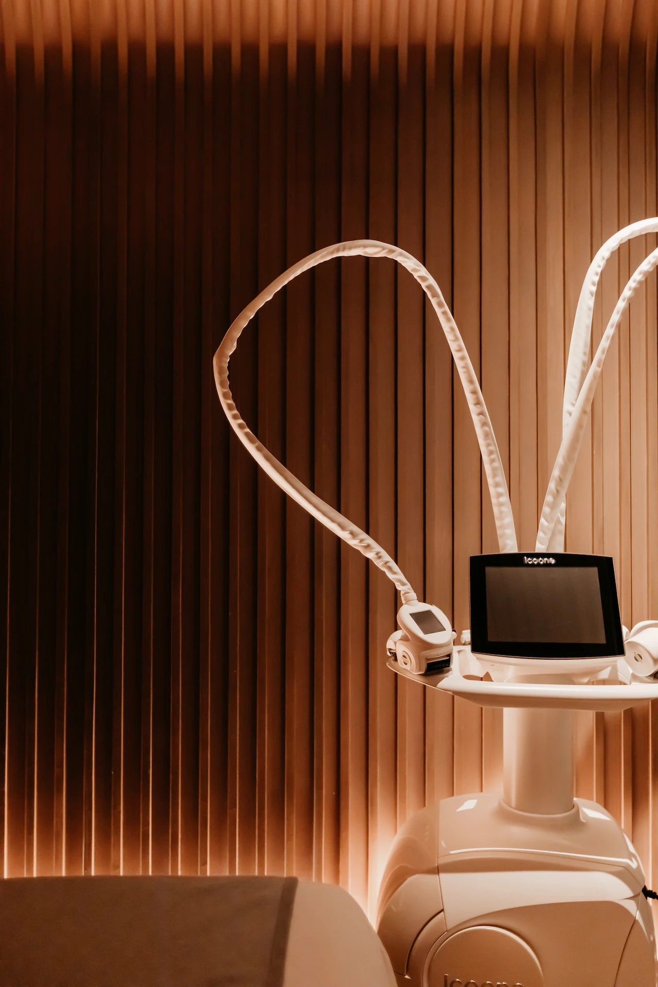 Modern aesthetic device with screen and applicators in wood-paneled room, evoking advanced wellness and serene design