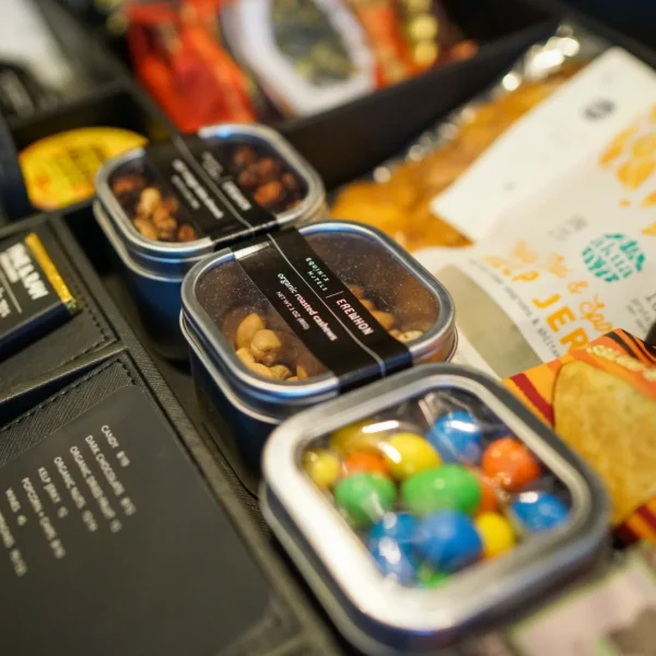 Drawer with assorted snacks including nuts, jerky, chips, and candy, arranged with price card in luxury hospitality setup