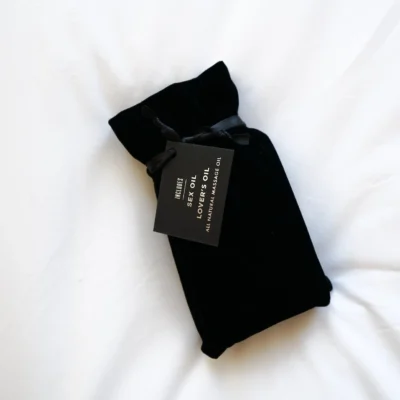Black velvet pouch with minimalist tag reading “Luxury Body Oil,” evoking indulgent self-care and curated in-room wellness