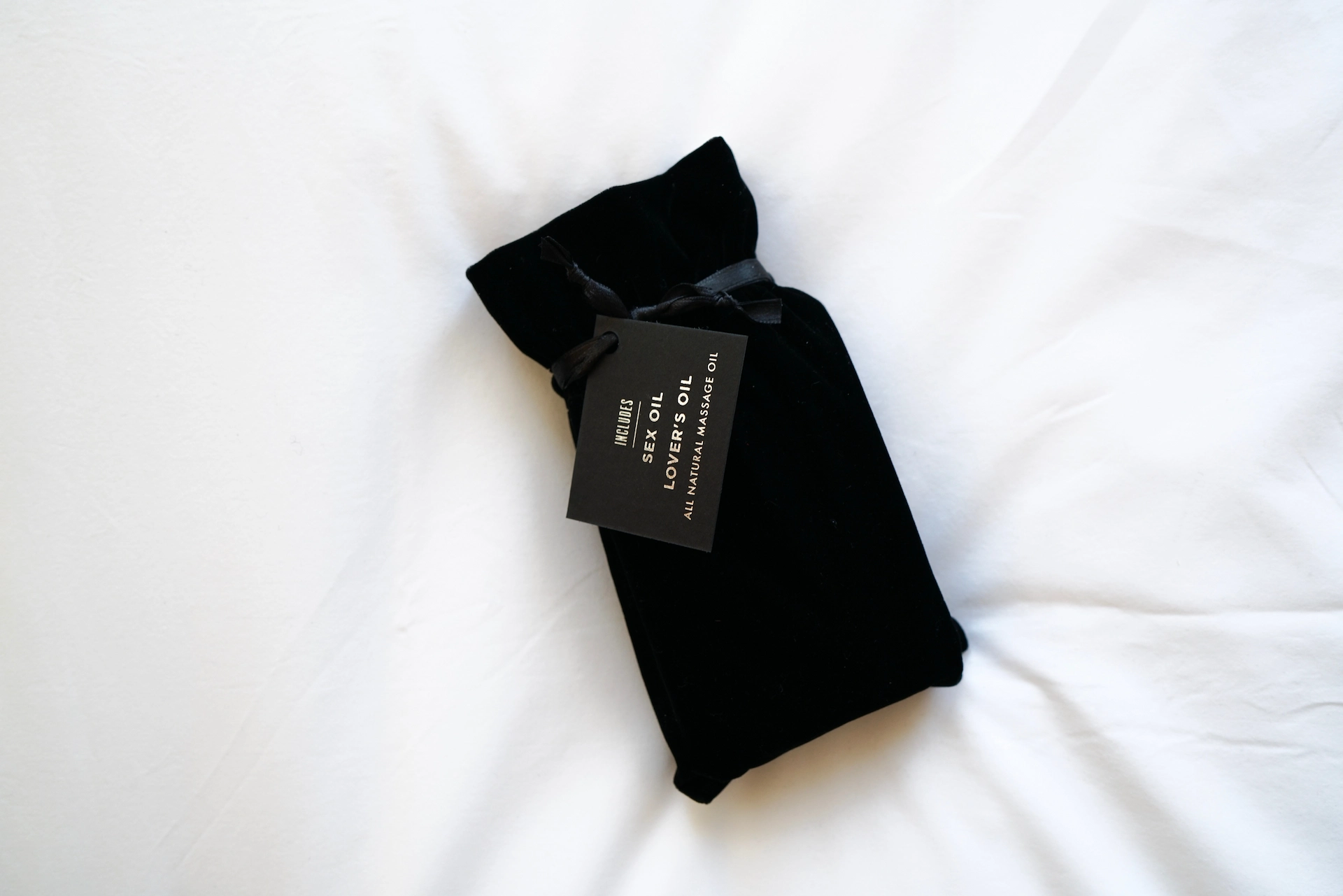 Black velvet pouch with minimalist tag reading “Luxury Body Oil,” evoking indulgent self-care and curated in-room wellness