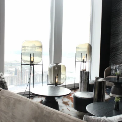 Modern lounge with suede sofas, sculptural lighting, and city views over water
