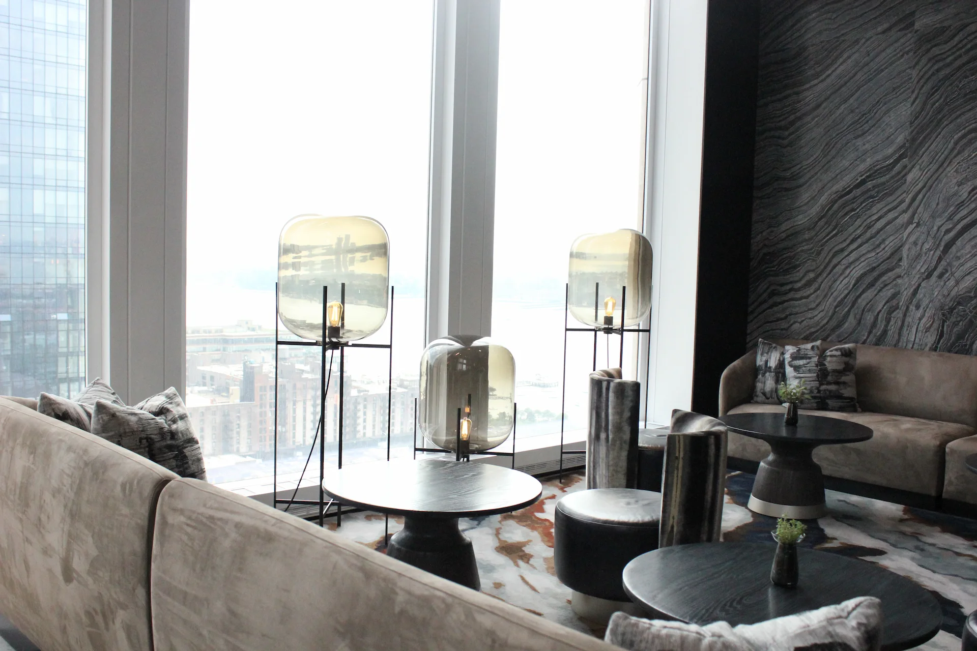 Modern lounge with suede sofas, sculptural lighting, and city views over water