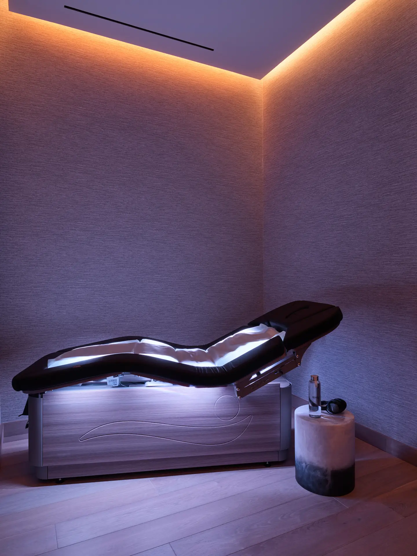 Minimalist spa room with contoured therapy bed and ambient lighting, evoking futuristic calm and sensory refinement
