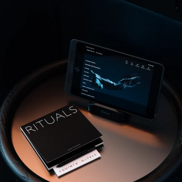 Round table with tablet showing Equinox Hotels wellness menu, next to branded booklets titled “Rituals”