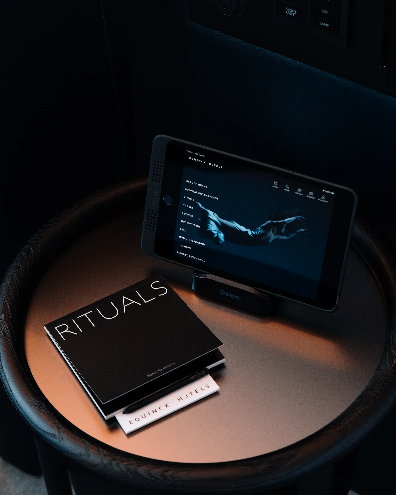 Round table with tablet showing Equinox Hotels wellness menu, next to branded booklets titled “Rituals”