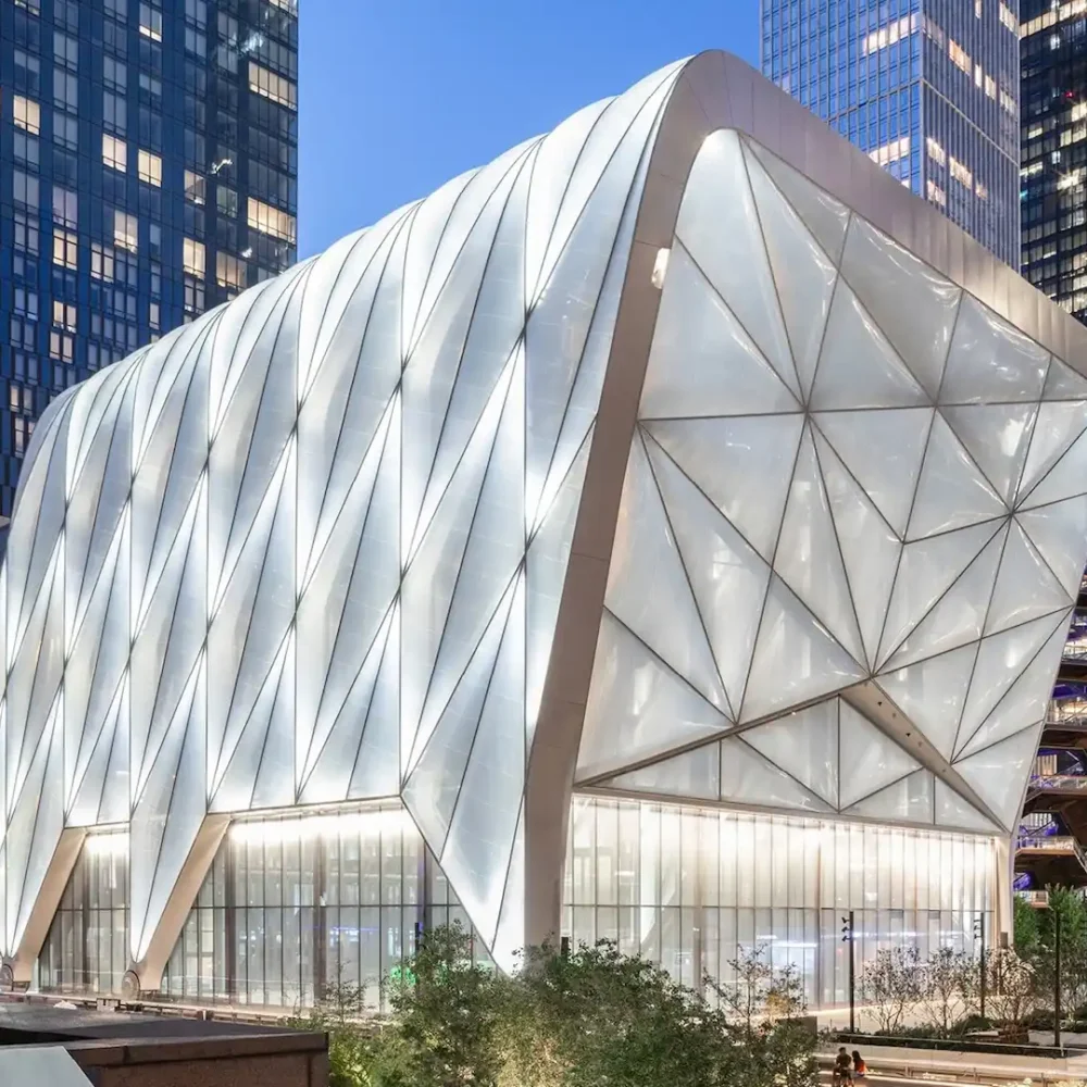 The Shed’s steel-framed shell illuminated at dusk, showcasing geometric design amid NYC skyscrapers