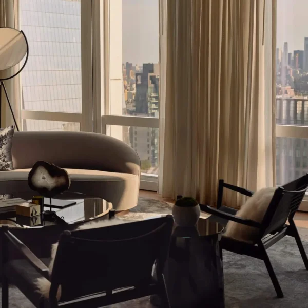 Elegant hotel lounge with curved sofa, panoramic city views, and warm daylight highlighting serene interior design