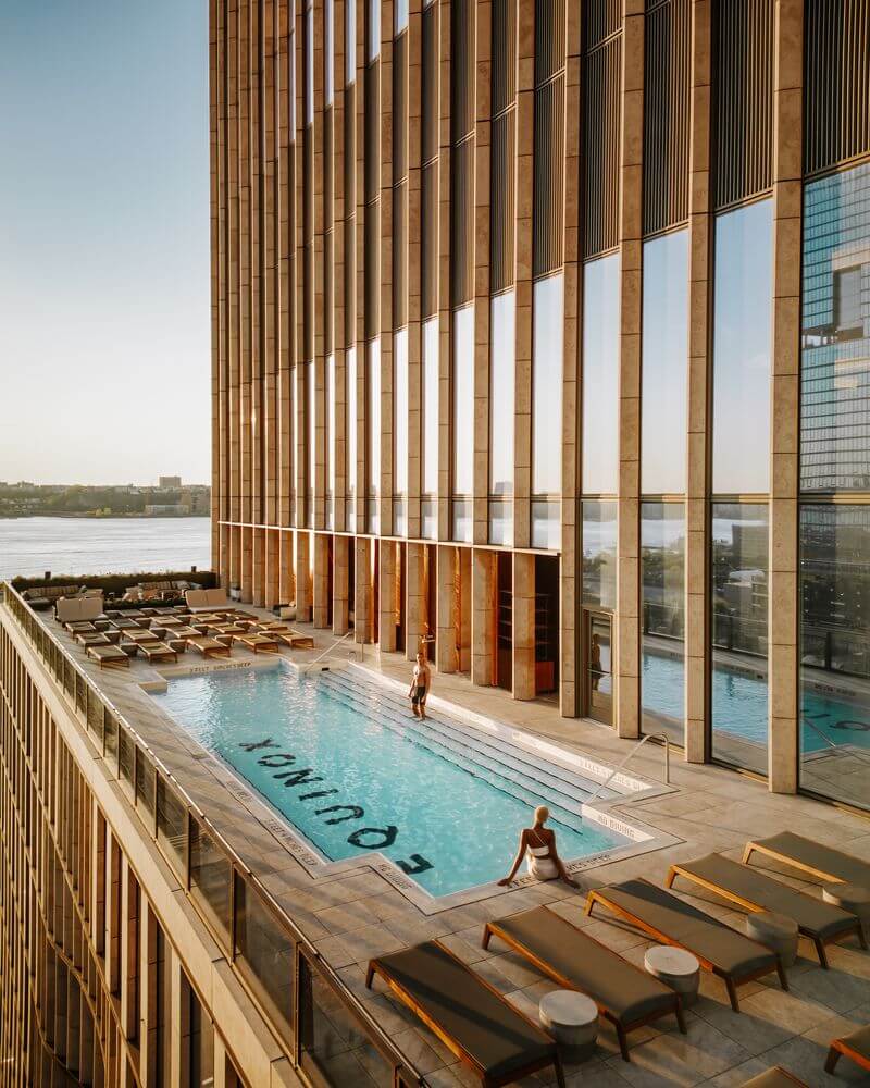 Equinox rooftop pool with city view, glass architecture, lounge chairs and guests enjoying luxury wellness