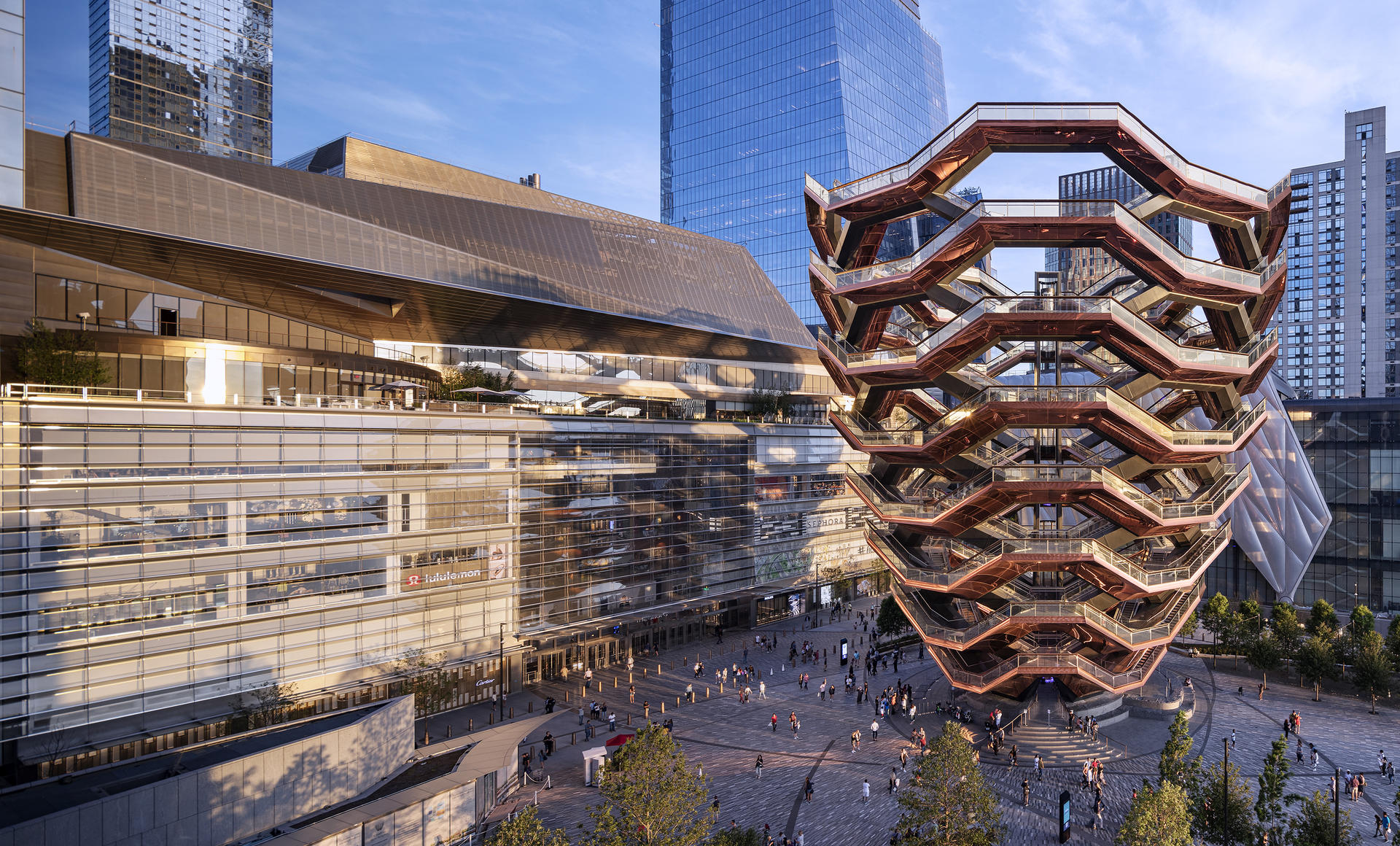 The Vessel at Hudson Yards in New York City with surrounding modern architecture, public plaza, and visitors below