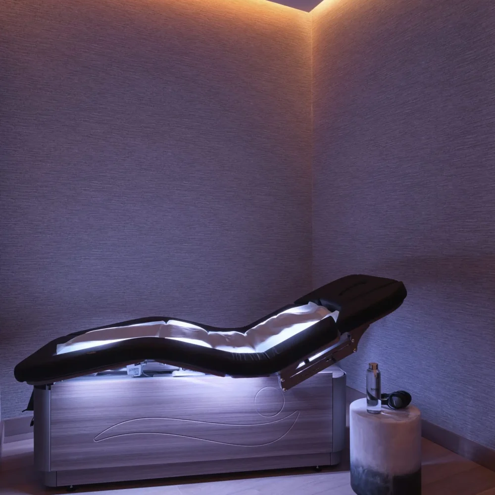 Modern wellness room at Equinox Hotels with illuminated therapy bed, ambient lighting, and calming decor